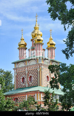 = St. Johannes der Täufer Kirche umrahmt von Bäumen im Sommer = Festliche Gateway der Geburtskirche St. Johannes der Täufer mit leuchtenden goldenen Zwiebeltürmen Stockfoto