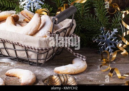 Hausgemachte Zucker Cookies Halbmond im Korb mit Vintage Cookie-Cuters Weihnachtsbaum über alten Holztisch serviert Stockfoto