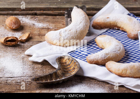 Hausgemachte Zucker Cookies Halbmond mit Vintage Ausstechformen, Mandeln und Textil über alten Holztisch serviert Stockfoto