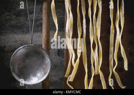 Die hausgemachte Pasta Linguine auf rustikale Küche mit Vintage Sieb Stockfoto