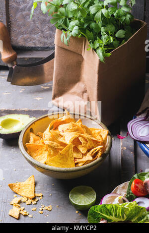 Abendessen im mexikanischen Stil mit Tortilla, Kräuter, Mais-Chips, Nachos und Guakomole, serviert auf grauem Holztisch Stockfoto