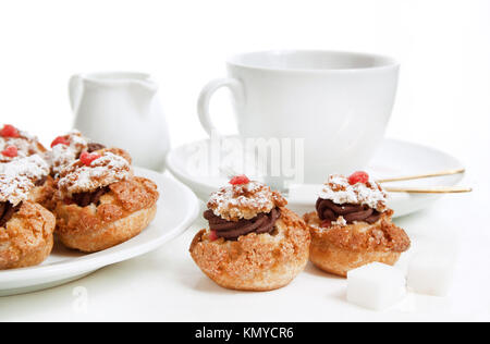 Mini-Kuchen mit Schokoladenmousse serviert mit Tasse Tee über Weiß Stockfoto