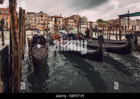 Günstig Gondeln um einen hölzernen Pier und Gebäude am Ufer des Grand Canal in einem verregneten Herbsttag, Venedig, Italien Stockfoto