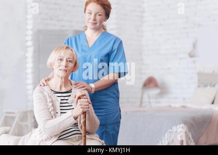 Eingedenk weibliche Betreuer neben Ihrem älteren stehenden Patienten Stockfoto