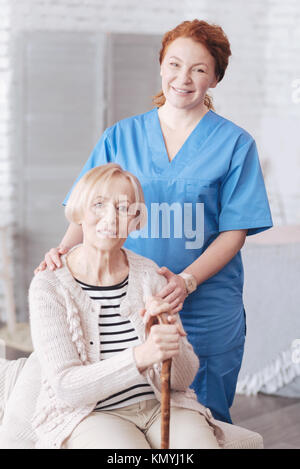 Ausschreibung reife Krankenschwester umarmen pensionierten Dame zu Hause Stockfoto