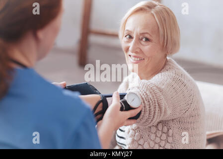 Glücklich pensionierte Dame lächelnd, während Ihr Blutdruck prüfen Stockfoto