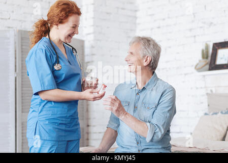 Radiant Betreuer salzen Pillen für fröhliche älterer Mann Stockfoto