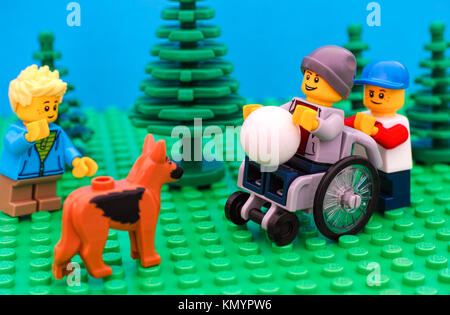 Tambow, Russische Föderation - Juli 30, 2016 Lego Junge im Rollstuhl mit Kugel bereit, mit seinen Freunden und Hund draußen zu spielen. Studio gedreht. Stockfoto