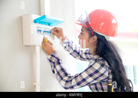 Hübsche asiatische Frau Elektriker oder Techniker prüfen oder prüfen Sie die elektrische Anlage Leistungsschalter auf Power Distribution Panel zu Hause. Stockfoto