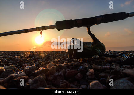 Angelausrüstung auf dem Sand bei Sonnenuntergang Stockfoto