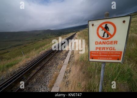 Die Bahn entlang der Snowdon Mountain im Snowdonia National Park, Wales. Warnschild entlang der Eisenbahn. Track. Gefahr peryol. Stockfoto