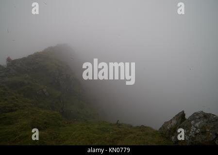 Blick vom Gipfel des Mount Snowdon an einem nebligen Tag, (Nebel/Nebel Wolken auf dem Gipfel des Snowdon) mit den Menschen in den Hintergrund Wandern auf dem Berg. Stockfoto