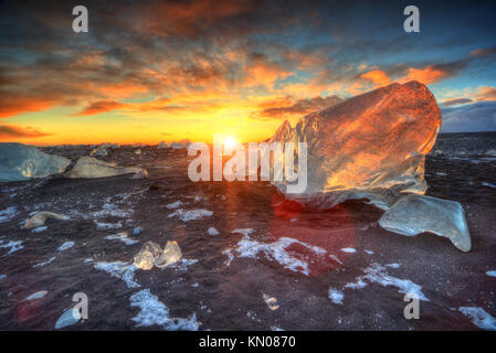 Schönen Sonnenuntergang über der berühmten Diamond Beach, Island. Dieser sand lava Strand ist voll von vielen riesigen Eis Edelsteine, in der Nähe der Gletscher Jokulsarlon platziert. Stockfoto