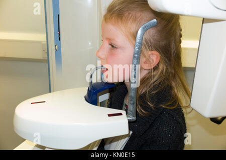 Kind im Alter von sieben Jahren in der Position zu einem zahnmedizinischen x-ray Scannen, Scannen von einem Panoramablick auf das x-ray Gerät/Maschine haben. UK. Kind ist Model Released. (92) Stockfoto