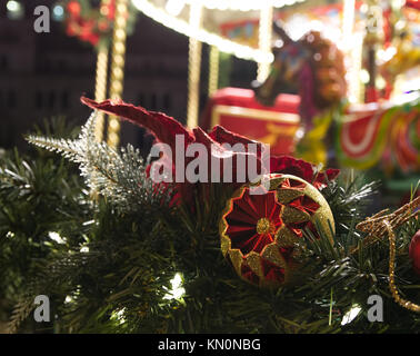 Weihnachten Dekorationen Kugeln auf Kranz mit Karussell unscharf im Hintergrund Stockfoto