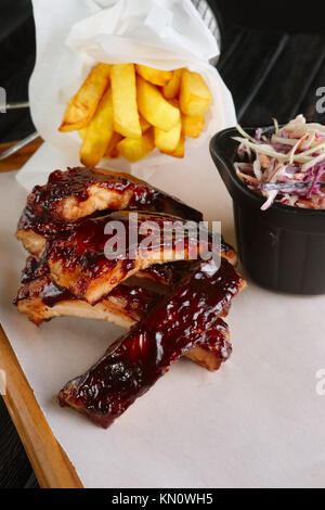 Gegrillte Rippchen mit gebratenen Kartoffeln und Rotkohl serviert. Stockfoto