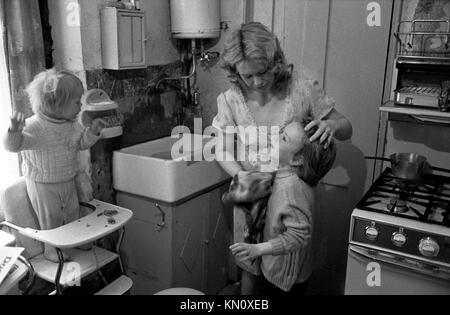 Slumwohnungen, Küche als Badezimmer, wird morgens von Mutter gewaschen. England der 1970er Jahre. Ascot Gas-Wasserkocher an der Wand über dem Butlerbecken 1972 Fulham, England 70er Jahre UK HOMER SYKES Stockfoto