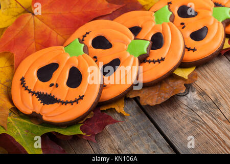 Hausgemachte Lebkuchen Kekse in der Form der Kürbisse für Halloween. Herbst Ahorn Blätter auf alten hölzernen Hintergrund. Stockfoto