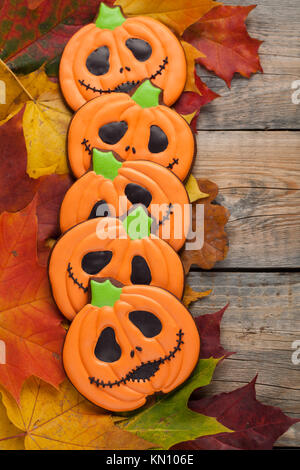 Hausgemachte Lebkuchen Kekse in der Form der Kürbisse für Halloween. Herbst Ahorn Blätter auf alten hölzernen Hintergrund. Ansicht von oben. Stockfoto