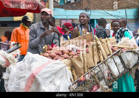 Einen kenianischen Mann mit einer Frau durch seinen Handwagen mit Süßkartoffeln für Transport, Nairobi, Kenia, Ostafrika Stockfoto