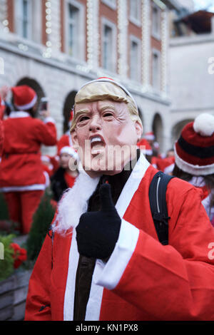 Covent Garden, London, UK. 9. Dezember 2017. Die jährlichen London Santacon zieht Hunderte von Santas an Central London. Eine Santa trägt ein Donald Trump (Präsident der Usa) Maske. Credit: Tony Farrugia/Alamy leben Nachrichten Stockfoto