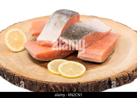 Gefrorenen lachs Fischfilets mit Zitronenscheiben auf Holz board isoliert. Stockfoto