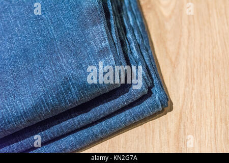 Jeans auf einer hölzernen Hintergrund gestapelt Stockfoto