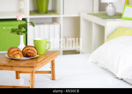 Frühstück im Bett, mit Gebäck auf einem Tablett und eine Rose in die Vase Stockfoto