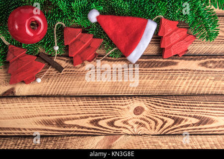 Weihnachten rot vintage Dekoration mit Weihnachtsmütze über Holzbohlen. Weihnachten vintage Hintergrund mit Text Raum Stockfoto