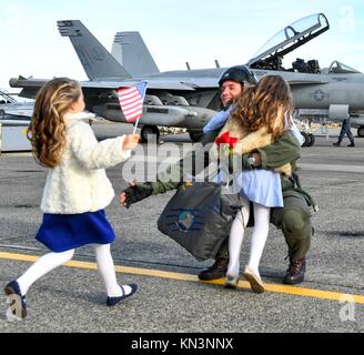 Ein U.S. Navy sailor Umarmungen hils Kinder bei der Ankunft im Naval Air Station Whidbey Island nach der Rückkehr von der Bereitstellung 4. Dezember in Oak Harbor, Washington 2017. (Foto durch Joseph E. Montemarano über Planetpix) Stockfoto