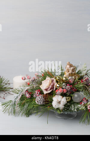 Dekorative Weihnachten Blumenstrauß mit Kerzen. In einem Glas Vase mit Tannenzweigen auf einem hellen Hintergrund Stockfoto