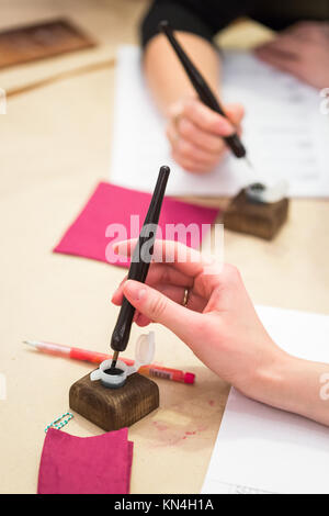 Malerei, Beruf, Hobby Konzept. Weibliche Kalligraphen arbeiten, sind sie Zeichnen und Schreiben mit schwarzer Tinte und Feder, spezielle Ausrüstung für erzeugen Dünne dunkle Linien Stockfoto