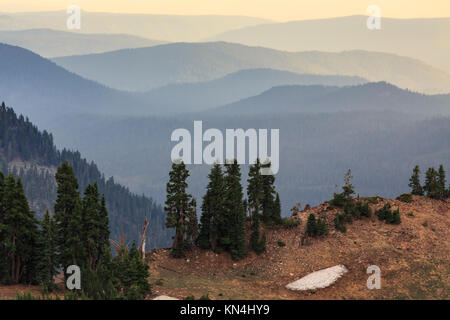 Die bergrücken der Cascade Mountains auf einem Hügel über dem Tal gesehen subtil in der Farbe von grünlich-blau und goldgelb wie die Sonne verblassen Stockfoto