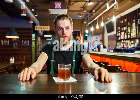 Bärtiger Mann am Tisch in der Kneipe Stockfoto
