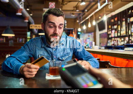 Betrunkener Mann Bezahlung mit Kreditkarte im Pub Stockfoto