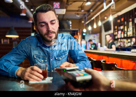 Betrunkener Mann Zahlen über NFC in Pub Stockfoto