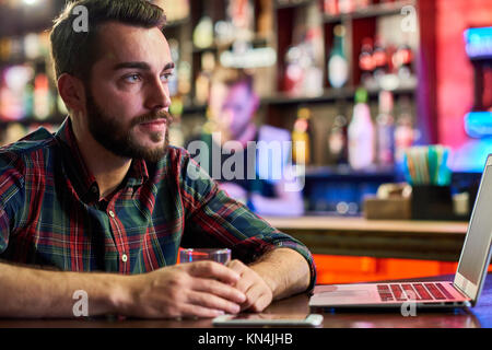 Junger Mann mit Laptop in Bar Stockfoto