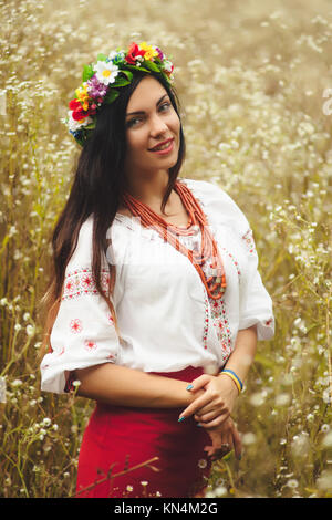 Schöne Frau in bunten ukrainischen Tracht halten Sie sich selbst und genießen Sie Sommer im Feld Stockfoto