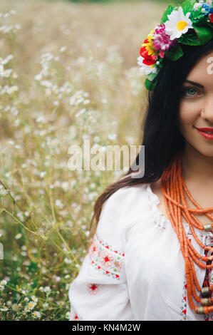 Schöne Frau in bunten ukrainischen Tracht halten Sie sich selbst und genießen Sie Sommer im Feld Stockfoto