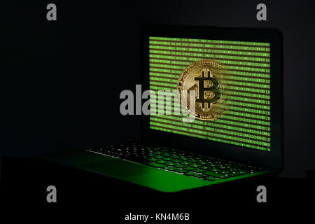 Symbol Bild cryptocurrency, digitale Währung, goldene physischen Münze bitcoin Laptop mit binären Code Stockfoto