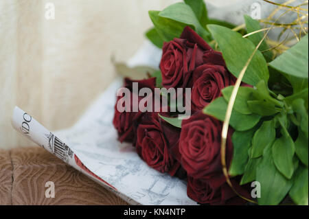 Luxus Strauß roter Rosen in Flower Shop Valentinstag Blumenstrauß aus roten Rosen. Rote Rosen eingewickelt in Papier auf hölzernen Tisch Hintergrund Stockfoto