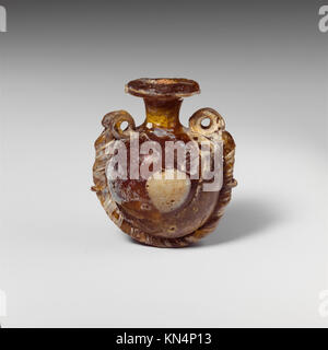 Diese Lentoid-Aryballos, eine antike Glasparfümflasche, demonstriert die Handwerkskunst der Glasherstellung mit einer eleganten Lentoid-Form und applizierten dekorativen Designs, die historische Ästhetik und kulturelle Praktiken widerspiegeln. Stockfoto