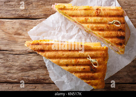 Sandwich mit frisch gegrilltem Fleisch und Käse gekocht, close-up auf Papier auf dem Tisch. Horizontal oben Ansicht von oben Stockfoto