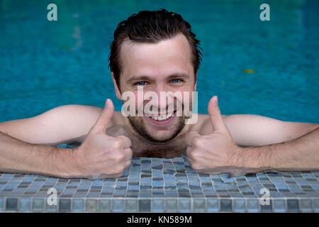 Gerne nass kaukasischen Mann in Pool zeigt Daumen nach oben. Stockfoto
