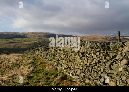 Eine Trockenmauer an greenholme in der Nähe von tabay mit den Cumbrian Fells in der Ferne. Stockfoto
