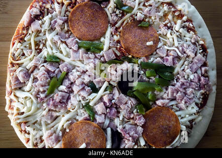 Vorbereitung für hausgemachte Pizza mit Schinken, Mozzarella und Gouda Käse, Schinken, Peperoni, Paprika, Champignons und Tomaten Stockfoto