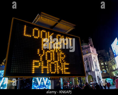 Polizei Schild am Piccadilly Circus Warnung vor Dieben in der Region sowie ihre Xmas Tipple aber kennen ihre Grenzen zu genießen und achten Sie auf Ihr Telefon Stockfoto