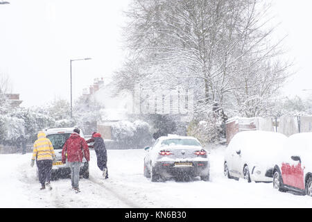 Menschen helfen Drücken klemmt Auto im Schnee Stockfoto