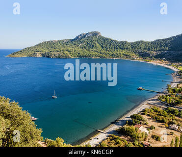 Wunderschöne Bucht mit türkisfarbenem Wasser, Sandstrand mit grünen Hügeln unter azurblauem Himmel umgeben Stockfoto