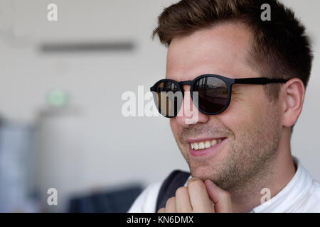 Ein lächelnder Mann in Sonnenbrille schaut aus dem Fenster auf dem Flughafen Stockfoto